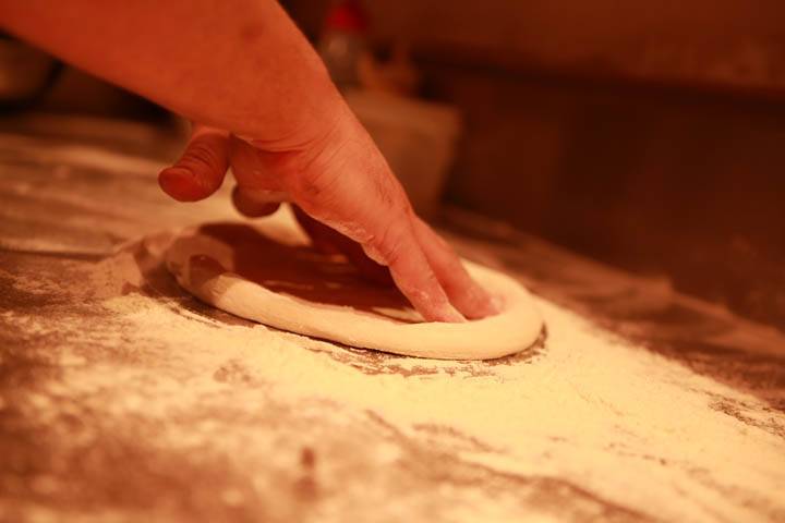 Hands shaping pizza dough