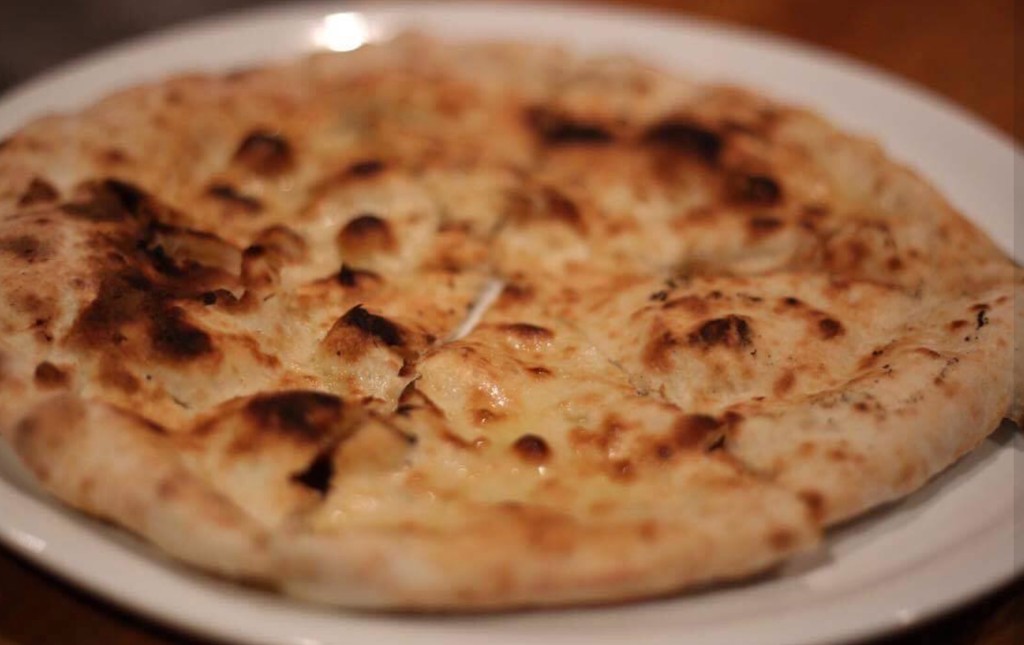 Pizza alle erbe—thin herb flatbread with olive oil on a charred crust